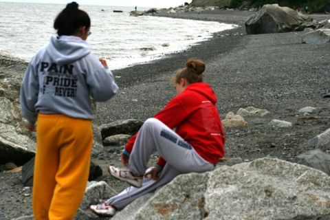 1990 Chevrolet Suburban - Two people relax on a rocky shore with the ocean in the background.