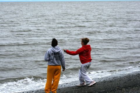 1990 Chevrolet Suburban - Two individuals observe the choppy water from a dark, pebbly shore.