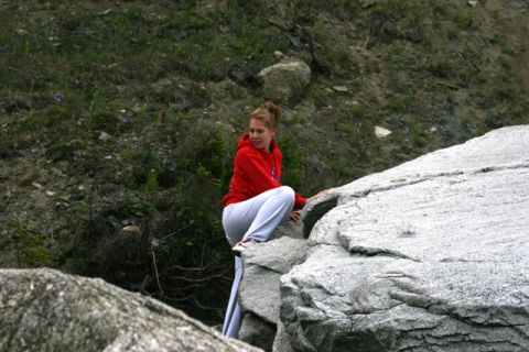 1990 Chevrolet Suburban - A young woman pauses while climbing a rocky incline outdoors.