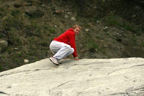 1990 Chevrolet Suburban - A person is crouching on a large rock in a natural outdoor setting.