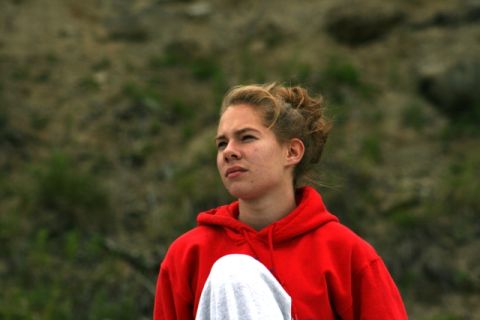 1990 Chevrolet Suburban - A young person in a red hoodie stands outdoors with a blurred background of hills and vegetation.