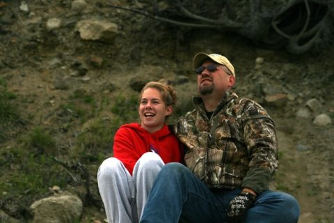 1990 Chevrolet Suburban - A man and a woman are sitting together outdoors, looking up and to the side.