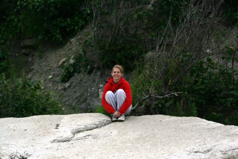 1990 Chevrolet Suburban - A person sits on a rock in a natural setting with dense foliage and a rocky embankment.