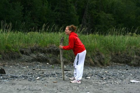 1990 Chevrolet Suburban - A young woman stands on a pebble beach, holding a large piece of driftwood.