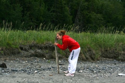 1990 Chevrolet Suburban - A young woman interacts with a piece of driftwood on a beach with tall grass in the background.