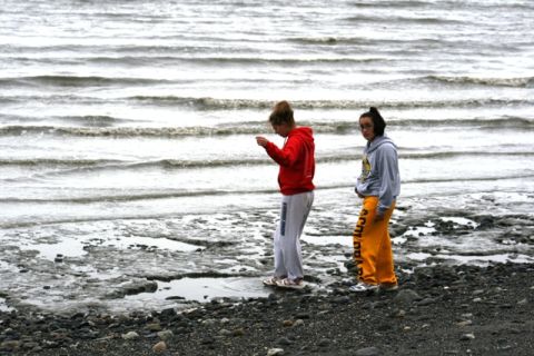1990 Chevrolet Suburban - Two young women observe the water on a rocky beach.