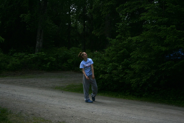 Person looking up in a wooded area with a dirt path
