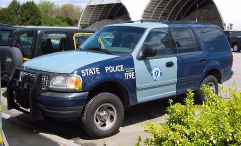 1998 Ford Crown Victoria - A two-tone Ford Expedition police SUV is parked outdoors next to other vehicles.