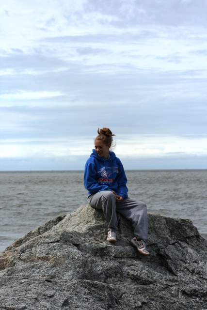 1990 Chevrolet Suburban - A young woman sits on a rock overlooking the water on an overcast day.