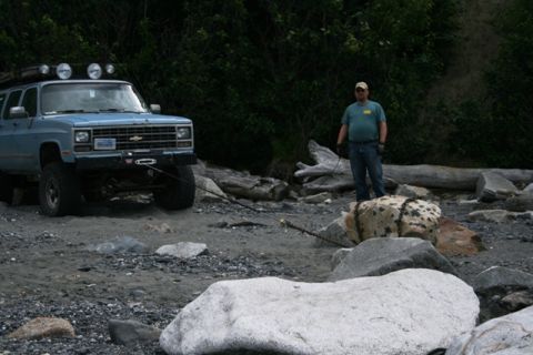 1990 Chevrolet Suburban - A man stands by a modified Chevrolet Suburban on a rocky shore, with a winch attached to a large boulder.