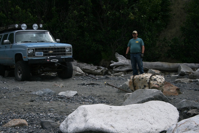 Light blue Chevrolet Suburban with winch and roof lights on a rocky beach