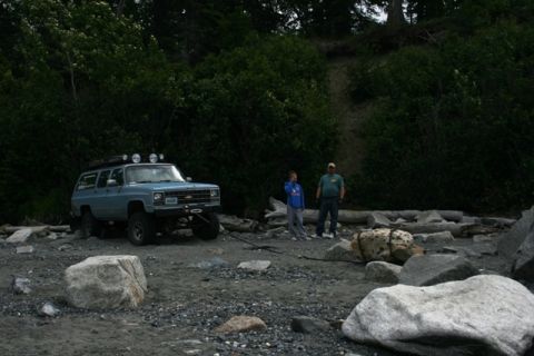 1990 Chevrolet Suburban - A light blue 1990 Chevrolet Suburban is parked on a rocky shore with two people standing nearby.