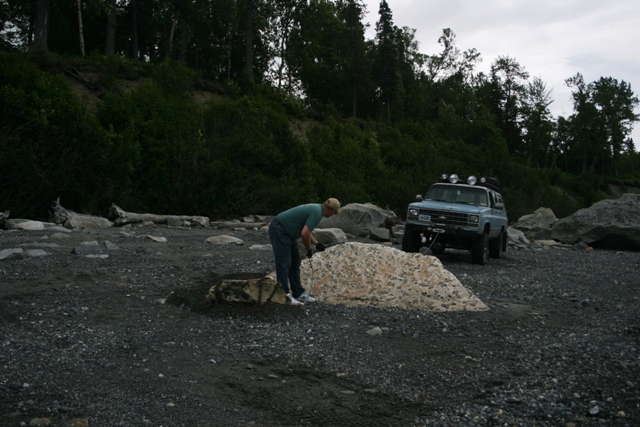Light blue SUV with winch and roof lights parked on a rocky beach near a person
