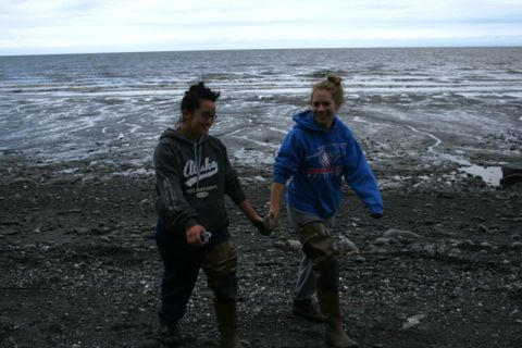 1990 Chevrolet Suburban - Two women wearing waders walk together on a rocky beach near the ocean.