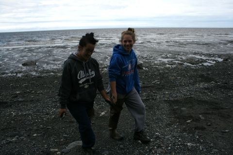 1990 Chevrolet Suburban - Two people walk on a rocky shore near the ocean under a cloudy sky.
