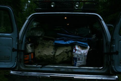1990 Chevrolet Suburban - The cargo area of an older SUV is filled with various items, including large rocks and camping equipment.