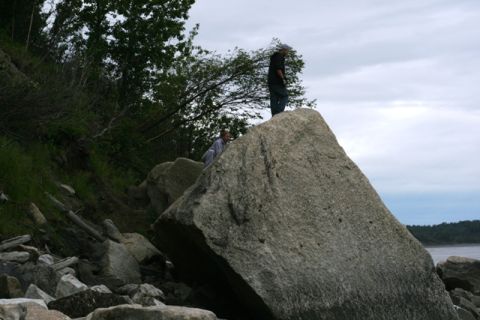 1990 Chevrolet Suburban - Two individuals stand atop large boulders near a body of water under a cloudy sky.
