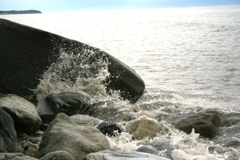 1990 Chevrolet Suburban - Waves crash against dark rocks on a bright, sunny day at Captain Cook State Park.