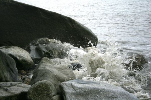 1990 Chevrolet Suburban - Water crashes against the rocky shore, creating a dynamic spray.