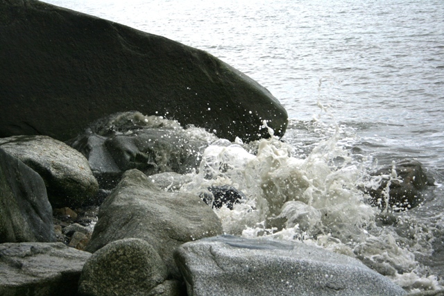 Waves splash against large rocks near the water's edge