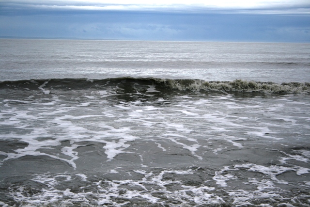 Waves crashing on the shore under a cloudy sky