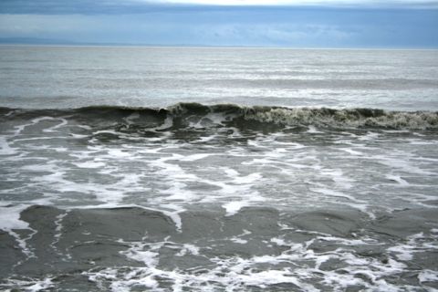 1990 Chevrolet Suburban - The ocean churns with waves and foam under a gray, cloudy sky.