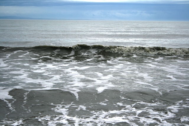 Ocean waves with white foam on a cloudy day