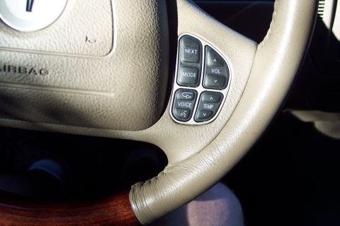 2001 Ford Crown Victoria - Interior view of a tan steering wheel audio controls for volume, mode, and next, along with climate controls for temperature.