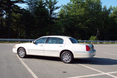 2001 Ford Crown Victoria - A white sedan is parked in a lot with trees in the background.