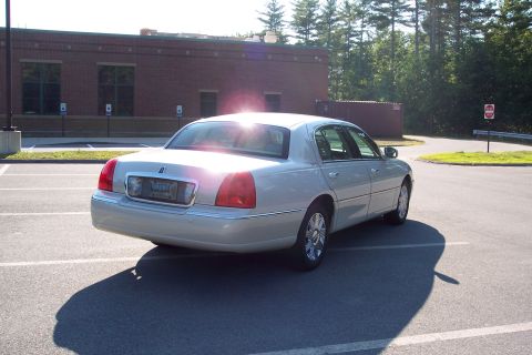 2001 Ford Crown Victoria - This silver sedan is parked in a lot with a brick building in the background.