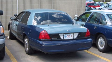 1998 Ford Crown Victoria - Two police cars, one a 1998 Ford Crown Victoria, parked in a lot.
