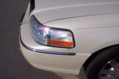 2001 Ford Crown Victoria - The front corner of a light-colored sedan shows a clear headlight and chrome bumper accents.