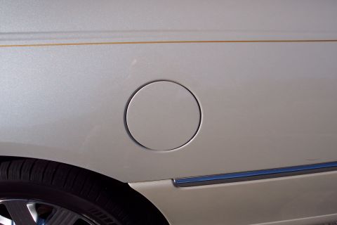 2001 Ford Crown Victoria - Fuel door on a silver vehicle, showing part of the rear wheel and trim.