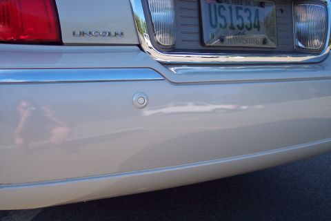 2001 Ford Crown Victoria - The rear of a Lincoln Town Car is visible, showing a license plate and parking sensor.