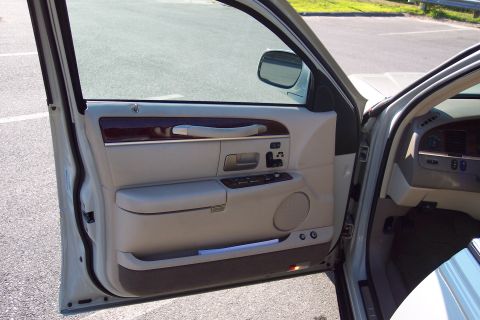 2001 Ford Crown Victoria - The interior of a Lincoln Town Car is shown with the driver's door open, revealing the door panel and dashboard details.