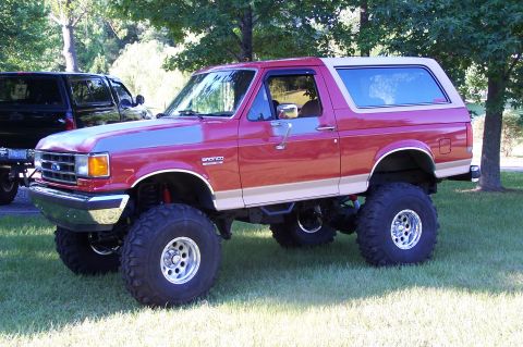 1990 Ford Bronco - This lifted 1990 Ford Bronco features a two-tone red and tan paint scheme and aggressive off-road tires.