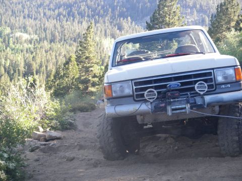 1991 Ford Bronco - A white Ford Bronco navigates a rocky, wooded mountain trail.