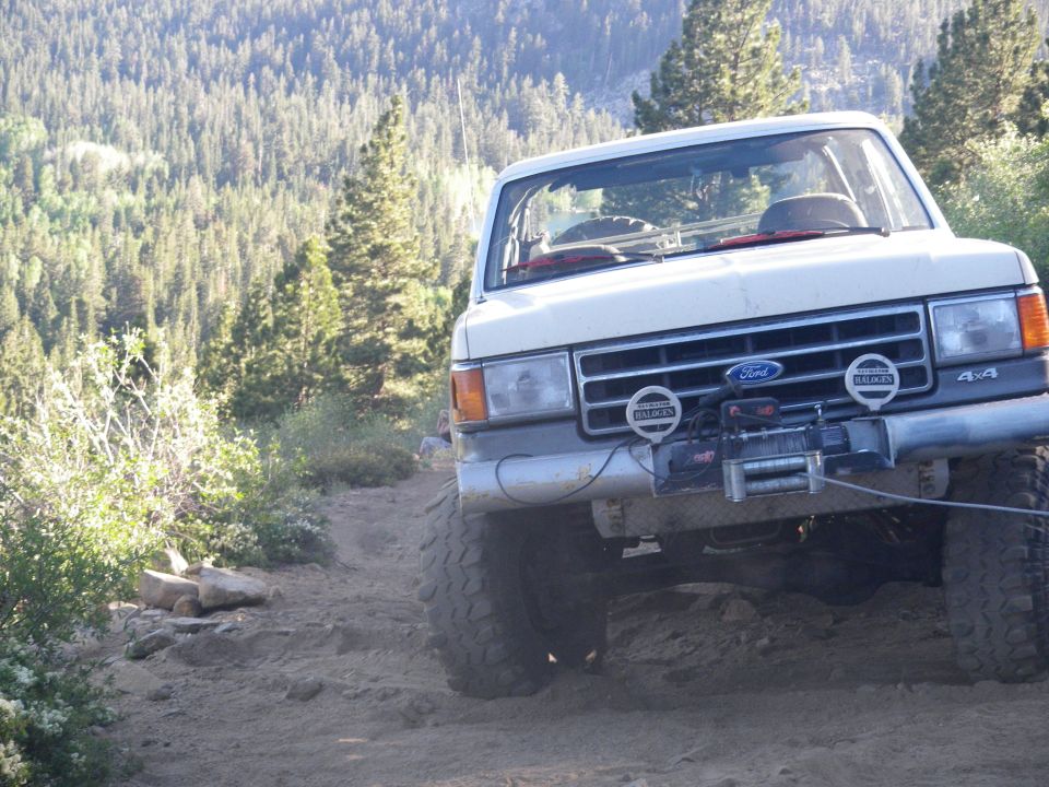 White Ford Bronco with a winch and off-road tires on a dirt trail