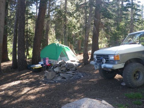 1991 Ford Bronco - Ford Bronco at a campsite in the woods with a tent and campfire.