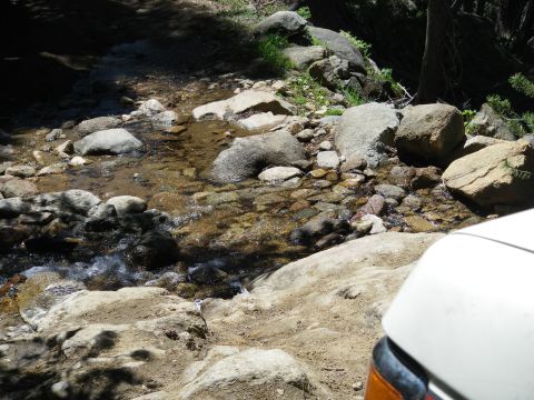 1991 Ford Bronco - A white vehicle navigates a rocky stream bed during an off-road excursion.