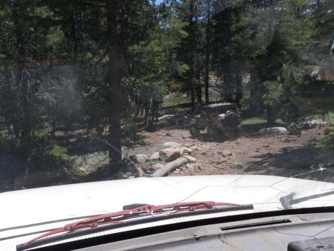 1991 Ford Bronco - Two vehicles navigate a wooded, rocky trail on a sunny day.