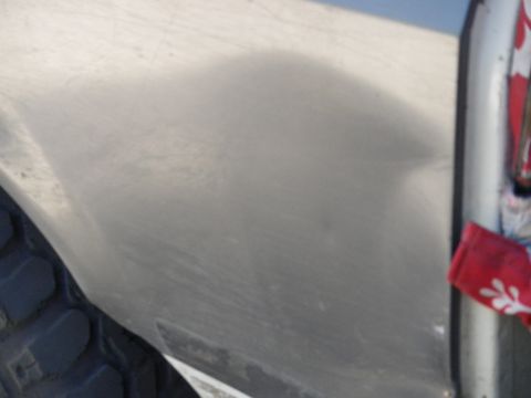 1991 Ford Bronco - A close-up view of a silver vehicle's side panel, showing a portion of the tire and a red fabric accessory.