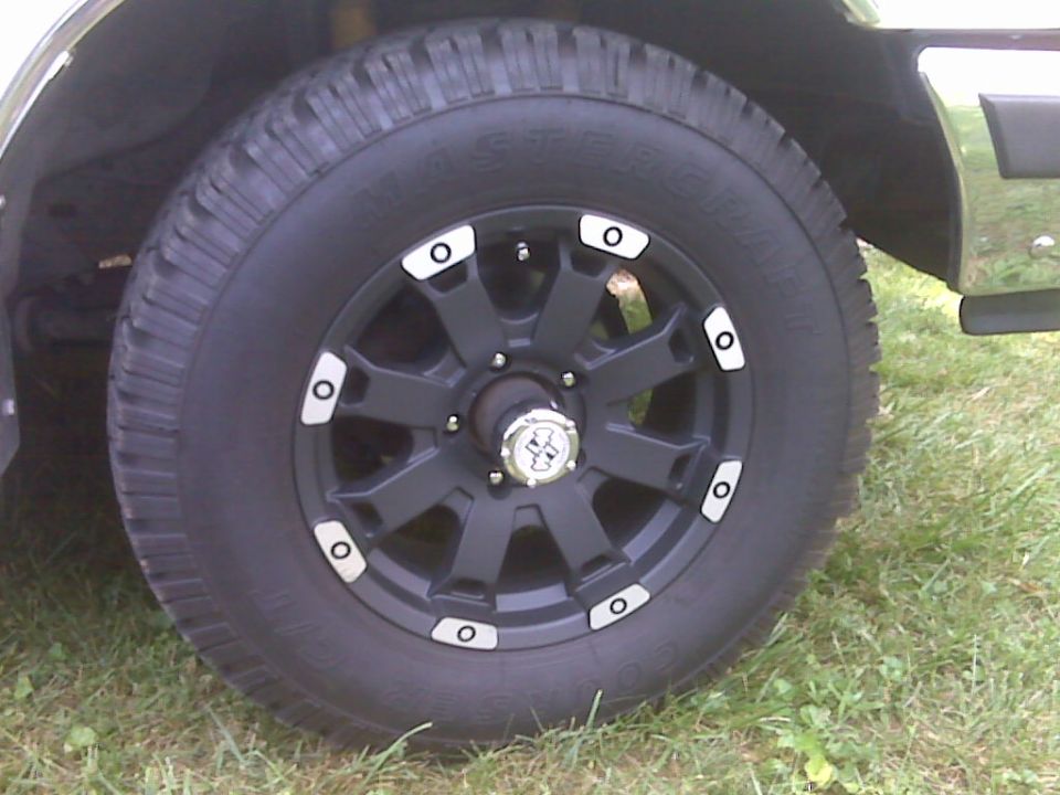 Mastercraft Courser C/T tire on black aftermarket wheel with chrome accents, parked on grass