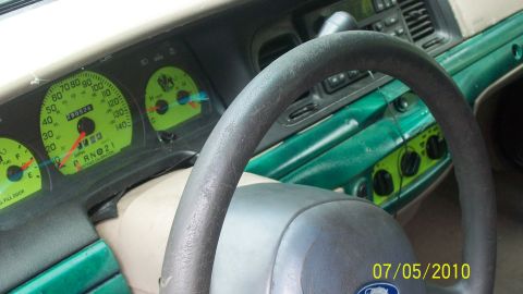 2004 Ford Crown Victoria - The interior of a 2004 Ford Crown Victoria features a green dashboard with a prominent steering wheel and illuminated gauges.
