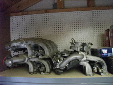 1994 Ford Probe - Engine intake manifold components are displayed on a shelf against a pegboard background.