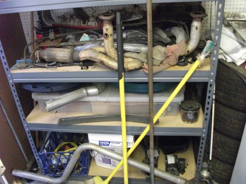 1994 Ford Probe - Automotive exhaust parts and tools are stored on metal shelving units.