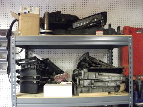 1994 Ford Probe - Various automotive parts are organized on metal shelving units in a workshop or storage area.