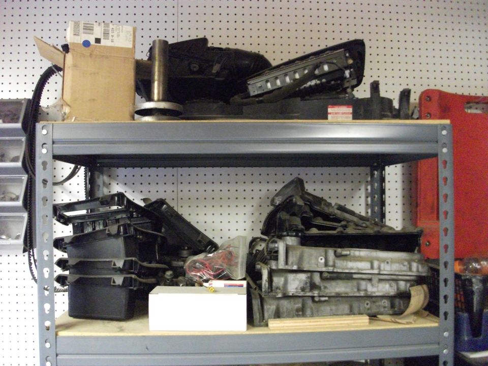 Shelves with various car parts, including an engine block and plastic components