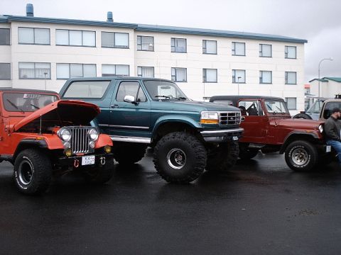 1996 Ford Bronco - Three SUVs are parked in front of a building on a cloudy day.