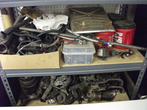 1994 Ford Probe - Various automotive parts are organized on metal shelves in a storage area.